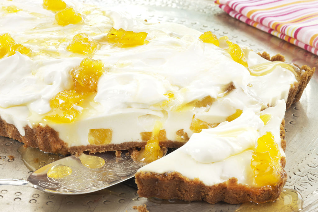 Ostekake med lettere fyll av kremost og yoghurt naturell. Vispet creme fraiche på toppen. Ananassirup både i ostefyllet og som pynt på toppen av ostekaken.